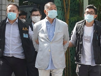 Hong Kong media tycoon Jimmy Lai, center, is arrested by police officers at his home in Hong Kong, August 10, 2020.