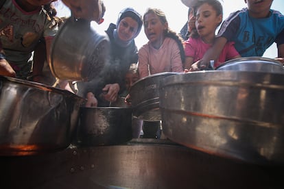 Palestinos desplazados, incluyendo mujeres y niños, esperan recibir alimentos distribuidos por organizaciones de ayuda humanitaria en la Ciudad de Gaza, el domingo.