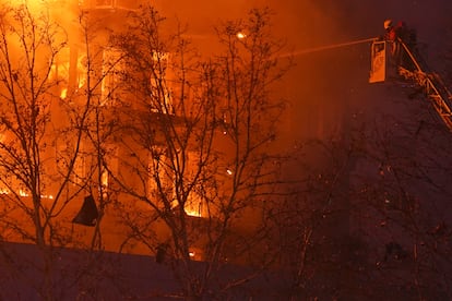 Los bomberos rocían el bloque de viviendas mientras arde.