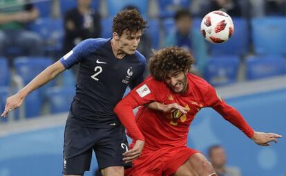 Benjamin Pavard (i) y Marouane Fellaini (d) intentan llevarse un balón de cabeza. 