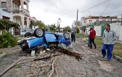 Vizinhos observam um carro virado por um tornado, em Havana (Cuba).