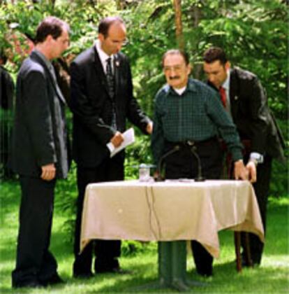 El primer ministro turco Bulent Ecevit recibe ayuda para sentarse antes de la rueda de prensa.