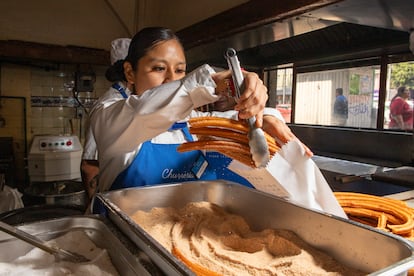 Una empleada baña de azucar con canerla churros de la churrería El Moro.