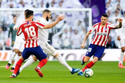 El delantero francés del Real Madrid, Karim Benzema (en el centro), trata de zafarse de dos jugadores del Atlético.