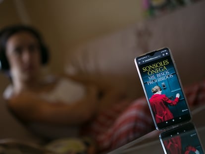 Una mujer escucha un audiolibro desde su teléfono móvil.