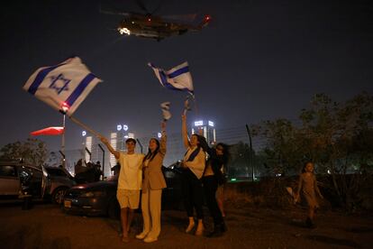 Varias personas ondean banderas de Israel mientras un helicóptero que transportaba rehenes israelíes liberados como parte de un acuerdo entre Israel y el grupo islamista palestino Hamas sale del Centro Médico Infantil Schneider en Petah Tikva.