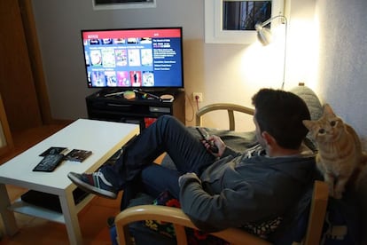 Un joven ve la televisión en el salón de su casa.