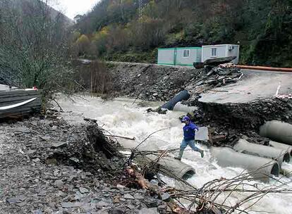 Un hombre intenta atravesar uno de los puentes que destrozó el río Valseco en Salientes (León).