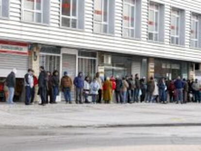 Varias personas forman una larga cola ante una oficina del INEM, a primera hora de la ma&ntilde;ana. 