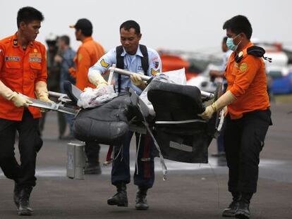 Miembros del equipo de rescate indonesio llevan restos del avión de Air Asia recuperados este lunes en el mar de Java. 