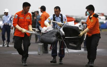 Miembros del equipo de rescate indonesio llevan restos del avión de Air Asia recuperados este lunes en el mar de Java.