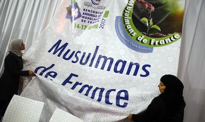 Unas mujeres musulmanas ajustan un cartel durante una exposici&oacute;n en la Feria Anual Musulmana de Francia en Paris la semana pasada.