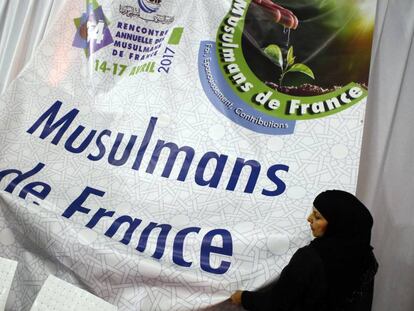 Unas mujeres musulmanas ajustan un cartel durante una exposici&oacute;n en la Feria Anual Musulmana de Francia en Paris la semana pasada.