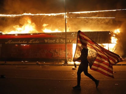 Un manifestante sujeta una bandera de Estados Unidos durante los disturbios en Minneapolis,