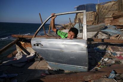 Un niño palestino sostiene una puerta de coche que ha encontrado cerca de la playa, en la ciudad de Gaza.