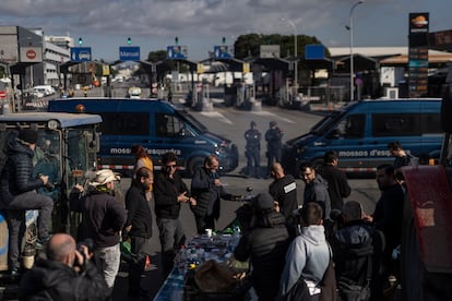 Agentes de Mossos d'Esquadra delante de los agricultores y tractores que han cortado uno de los accesos a Mercabarna.