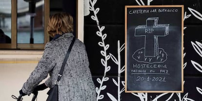 Una mujer observa un cartel colocado en una cafetería de Valencia