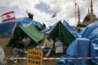 Manifestantes en un campamento instalado en el centro de Beirut, tras un cartel en el que se lee "Siria, régimen asesino".