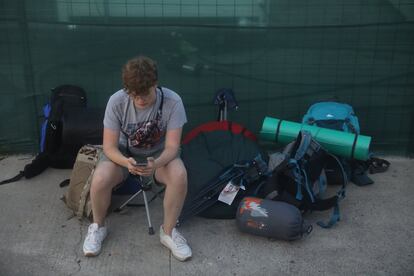 Un joven mira su móvil, junto a su equipaje, en Burriana.