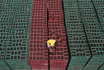 Un operario coloca cajas de cerveza antes de cargarlas en un camión dentro de un depósito de San Miguel, en Manila (Filipinas).