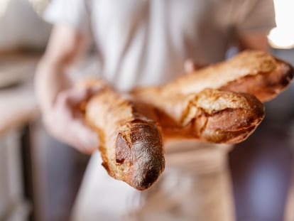 Un panadero sostiene tres barras de pan en París, Francia.