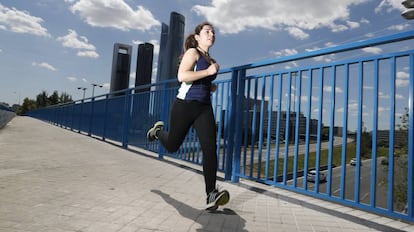 Una mujer corre por una calle de Madrid, con las Cuatro Torres de fondo.