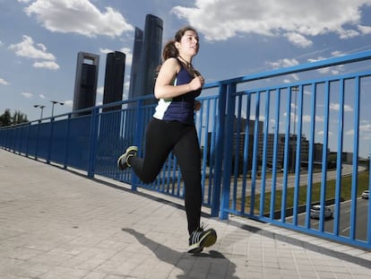 Una mujer corre por una calle de Madrid, con las Cuatro Torres de fondo.