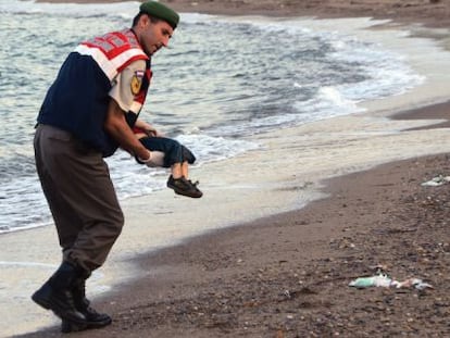 Un policía recoge el cadaver de un niño en una playa de Turquía.