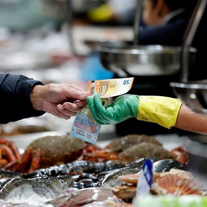 A CORUÑA, 19/12/24.- Un hombre pagael pescado adquirido en uno de los puestos del mercado de la plaza de Lugo, en la ciudad de A Coruña, donde comienza a notarse el incremento de clientes que adelantan las compras de cara a las fiestas de la Navidad, con un "buen ritmo de ventas y producto freso de primera calidad". EFE/Cabalar