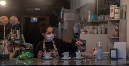 Una camarera sirve cafés en un bar.