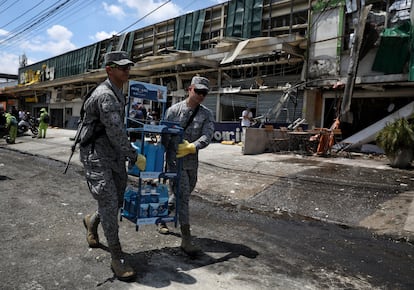 Dos soldados ayudan en la zona del atentado, en Cali.