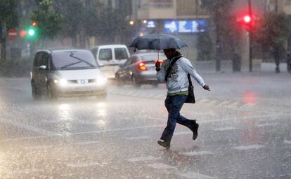 Un joven corre entre una cortina de lluvia en un pueblo de la Comunidad Valenciana durante la mañana de este lunes.