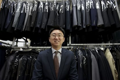 Man Han-il, fundador de The Open Closet posa junto a los trajes donados que muchos jóvenes utilizan para acudir a entrevistas de trabajo.