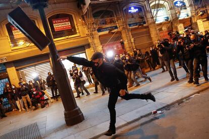 Con pancartas en las que se podía leer "Secuestrado por el Estado ¡Todos a la calle! ¡Conquistemos su libertad!" o "Pablo Hasél, Libertad. Fuera la Justicia Franquista", la concentración ha comenzado con un ambiente festivo con cánticos para reclamar la salida de prisión del rapero catalán, pero luego ha derivado en violencia contra las fuerzas del orden. En la imagen, un joven manifestante tira un contenedor, este miércoles en Madrid.