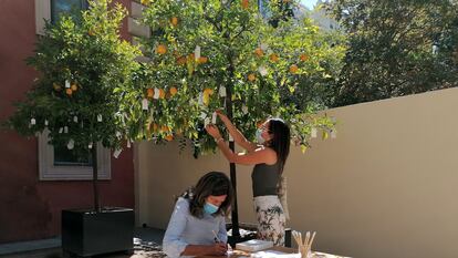 Dos visitantes cuelgan sus deseos en 'Wish Tree', el proyecto de Yoko Ono que se expone en el museo Lázaro Galdiano, en Madrid. I.U