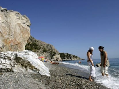 Dos jóvenes se mojan los pies en la playa de Cantarriján, naturista y natural, en Almuñecar.