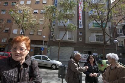 Ana, a la izquierda, propietaria de dos pisos en el edificio 'ocupado' en Nou Barris, al fondo.