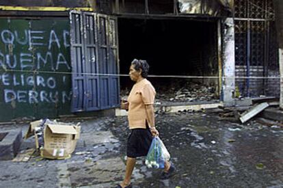 Una mujer pasa ante una tienda saqueada durante el fin de semana en Caracas.