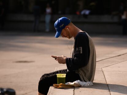 Un joven extranjero mira la pantalla de su teléfono celular, en Ciudad de México.