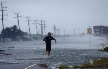 Un hombre intenta cruzar una carretera luchando contra la fuerza del viento del huracán 'Arthur' a su paso por Nags Head, en Carolina del Norte.