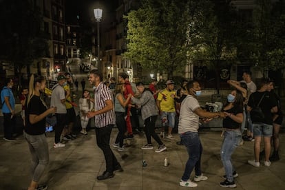 Un grupo de jóvenes baila pasadas las doce de la noche en la plaza de Isabel II, junto a Opera, en Madrid.