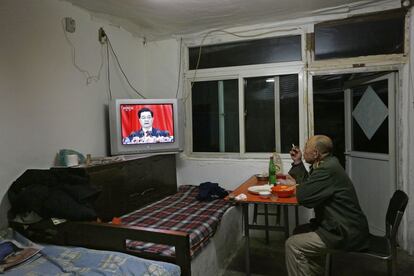 Un hombre cena en su casa de Pekín mientras retransmiten el mensaje de apertura del presidente.