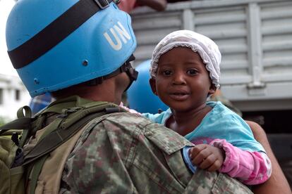 Un casco azul introduce a una niña en un camión para evacuarla del campamento de instalado en Puerto Príncipe, ante la llegada del huracán Tomas.