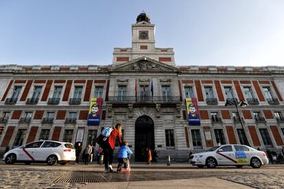 Una madre y su hijo pasean por la Puerta del Sol de Madrid con la Casa de Correos, sede del Gobierno regional, al fondo. En su fachada, este lunes se han colocado dos pancartas pidiendo la libertad del líder opositor venezolano Leopoldo López, encarcelado en su país.