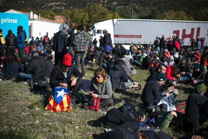 Manifestantes independentistas descansas sentados en el césped, cerca de La Jonquera.