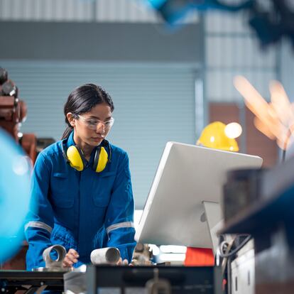 Female Industrial engineer working on desktop computer in robotic welding testing area of research and development in automobile industry. Productivity improvement concepts.