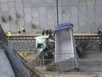 Fotografía facilitada por el Ayuntamiento de Madrid que muestra a varios efectivos del cuerpo de bomberos junto al camión que ha caído esta tarde, desde unos doce metros de altura, a las vías del AVE Madrid-Barcelona, y cuyo conductor, un hombre de 58 años ha muerto.