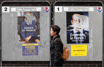 Una mujer pasa por delante de carteles electorales da&ntilde;ados en Par&iacute;s