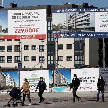 Varios viandantes pasan ante una promoción de viviendas en construcción el barrio madrileño de El Cañaveral.