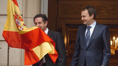 El presidente de Cantabria, Miguel Ángel Revilla, besa la bandera española junto a José Luis Rodríguez Zapatero.